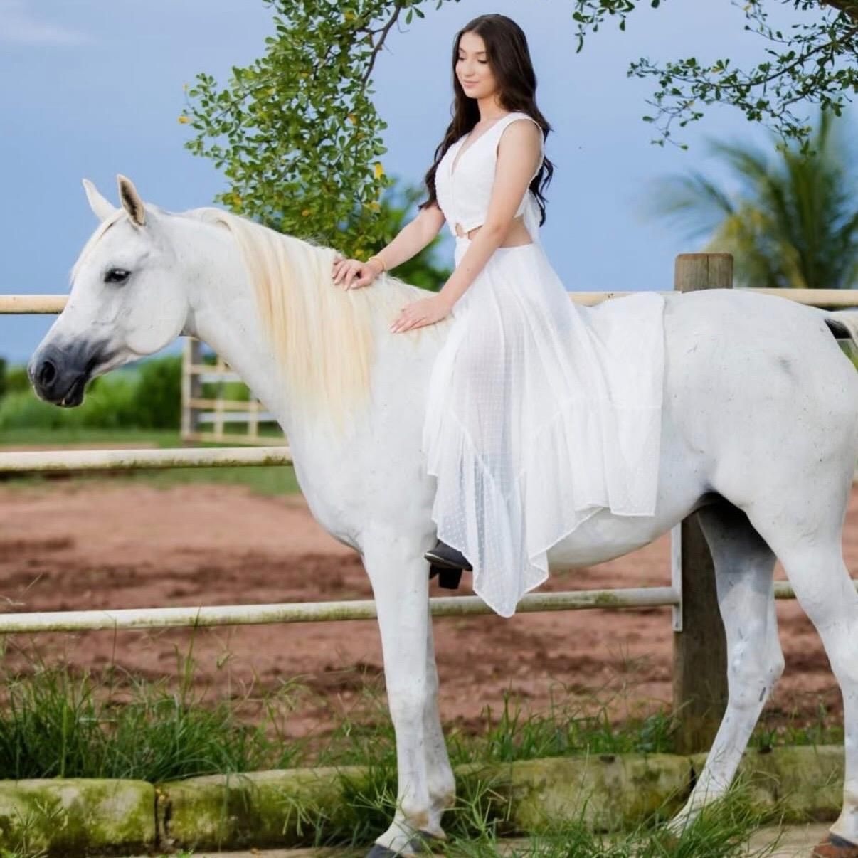 Jovem de vestido branco sobre um cavalo branco no Arabian Photography Studio