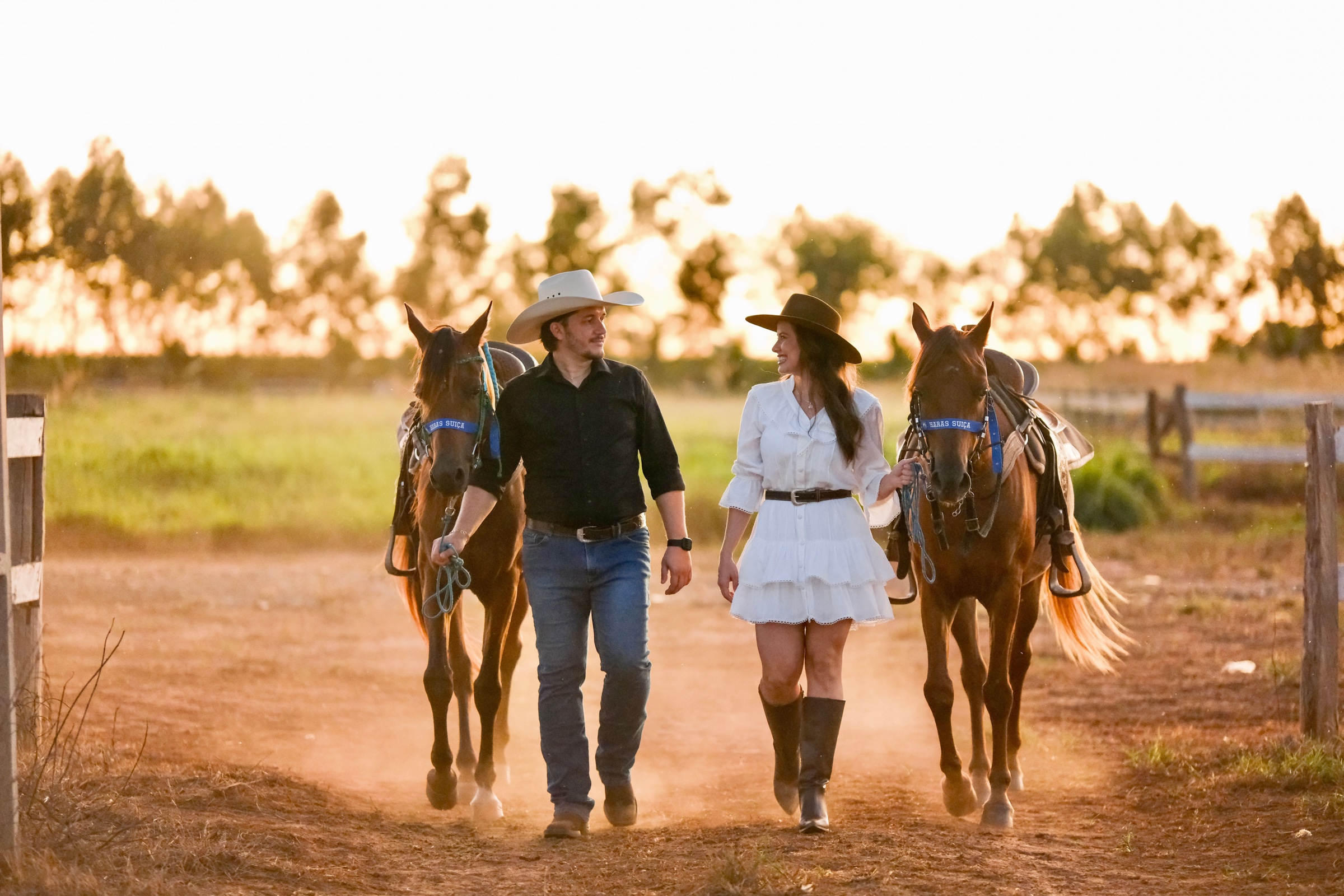 Casal caminhando com dois cavalos ao pôr do sol no Arabian Photography Studio